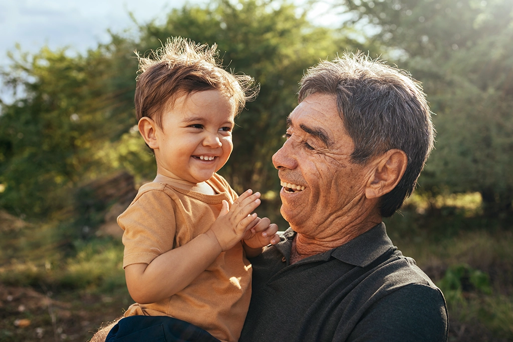 Grandfather Holding Grandchild While On Farm